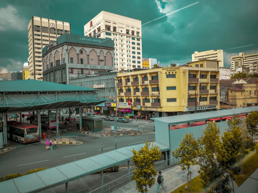 A bustling urban intersection with Lavana Hotel, bus station, and vibrant street life.
